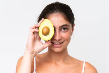 Young Pretty caucasian woman isolated on white background holding an avocado while smiling. Close up portrait