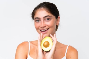 Young Pretty caucasian woman isolated on white background holding an avocado while smiling. Close up portrait