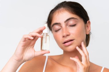 Young Pretty caucasian woman isolated on white background holding a serum. Close up portrait