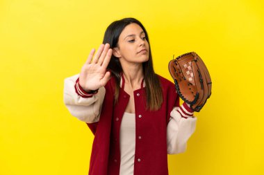 Young caucasian woman playing baseball isolated on yellow background making stop gesture and disappointed