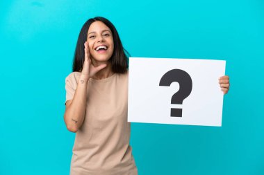 Young woman over isolated background holding a placard with question mark symbol and shouting