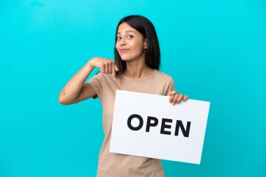 Arka planda izole edilmiş genç bir kadın. Elinde açık yazılı bir pankart var ve onu işaret ediyor.