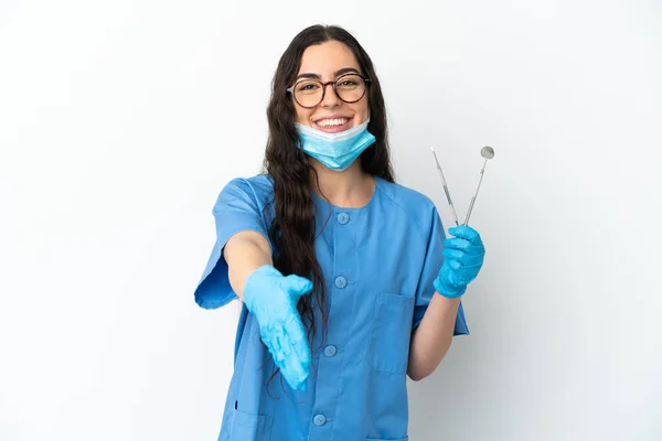 Młoda Kobieta Dentysta Trzyma Narzędzia Izolowane Białym Tle Ściskając Dłonie — Zdjęcie stockowe