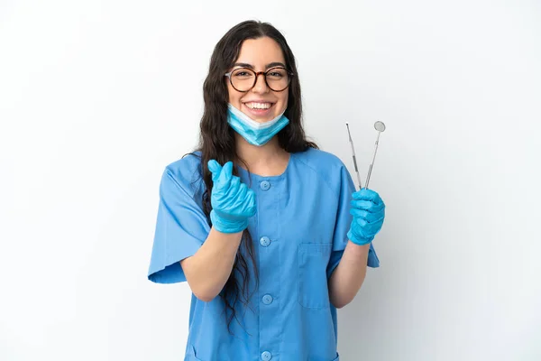 年轻的女牙医拿着被白色背景隔离的工具做着赚钱的手势 — 图库照片