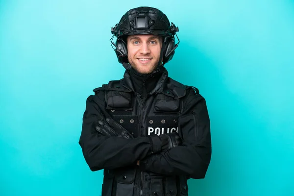 SWAT caucasian man isolated on blue background keeping the arms crossed in frontal position