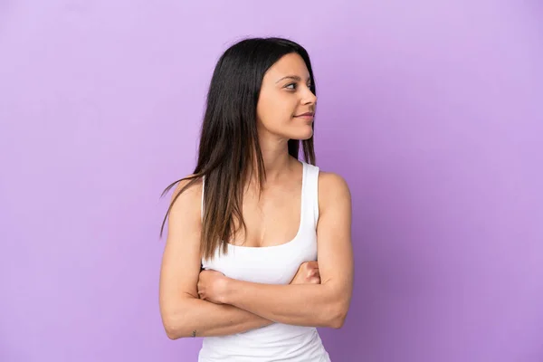 Young caucasian woman isolated on purple background looking to the side