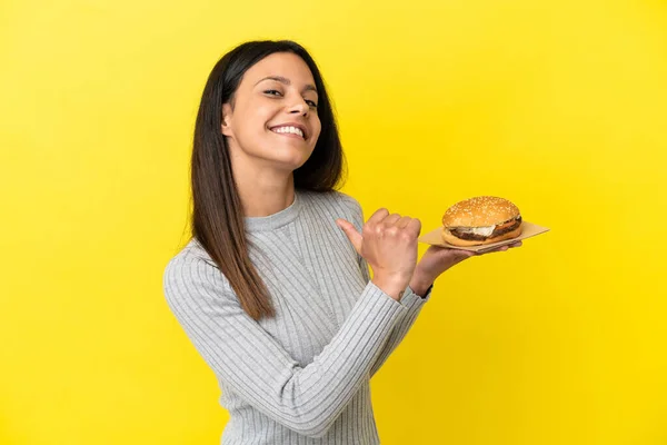 Young Caucasian Woman Holding Burger Isolated Yellow Background Proud Self — Stock Photo, Image