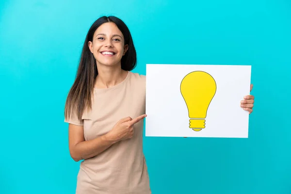 Young Woman Isolated Background Holding Placard Bulb Icon Pointing — Stock Photo, Image