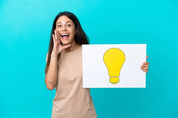 Young Woman Isolated Background Holding Placard Bulb Icon Shouting — Stockfoto