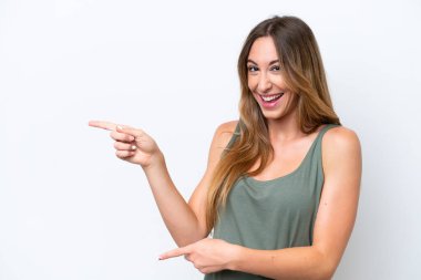 Beyaz arka planda izole edilmiş genç beyaz kadın şaşırmış ve işaret ediyor.