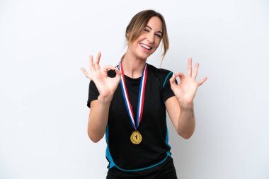 Beyaz arka planda madalyalı beyaz bir kadın parmaklarıyla iyi bir işaret gösteriyor.