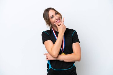 Beyaz arka planda madalyalı beyaz bir kadın gülümsüyor.