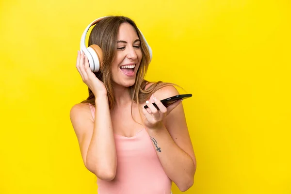 Joven Mujer Caucásica Aislada Sobre Fondo Amarillo Escuchando Música Con —  Fotos de Stock