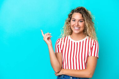 Girl with curly hair isolated on blue background happy and pointing up