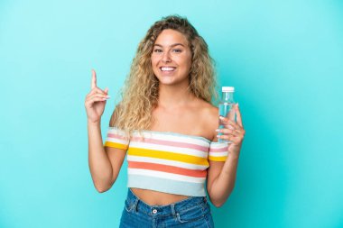 Young blonde woman with a bottle of water isolated on blue background showing and lifting a finger in sign of the best