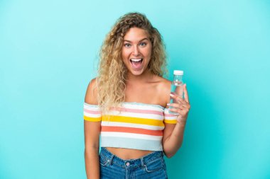 Mavi arka planda su şişesi olan sarışın genç bir kadın. Şaşırtıcı bir yüz ifadesi var.