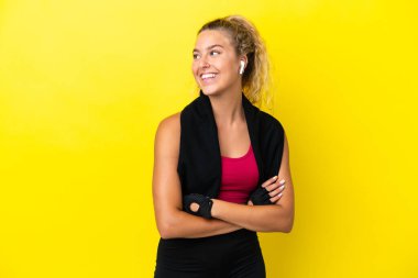 Sport woman with towel isolated on yellow background looking side