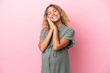 Kıvırcık saçlı kız pembe arka planda izole edilmiş hamile ve mutlu.