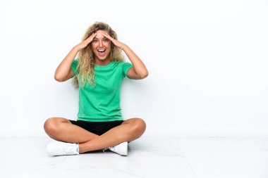 Girl with curly hair sitting on the floor with surprise expression