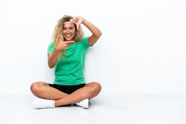 Girl with curly hair sitting on the floor focusing face. Framing symbol