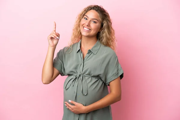 Chica Con Pelo Rizado Aislado Sobre Fondo Rosa Embarazada Apuntando —  Fotos de Stock