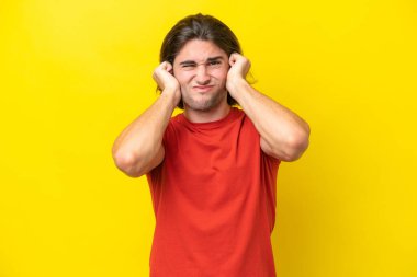 Caucasian handsome man isolated on yellow background frustrated and covering ears