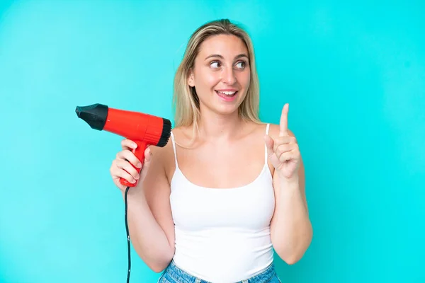 Mujer Caucásica Joven Sosteniendo Secador Pelo Aislado Sobre Fondo Azul —  Fotos de Stock