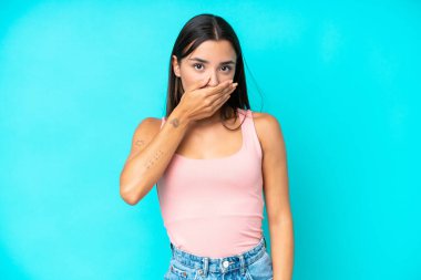 Mavi arka planda izole edilmiş, ağzı elle kaplanmış beyaz bir kadın.