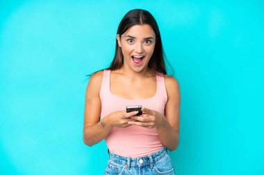 Mavi arka planda izole genç beyaz kadın şaşırdı ve bir mesaj gönderiyor.