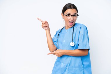 Young nurse woman isolated on white background surprised and pointing side
