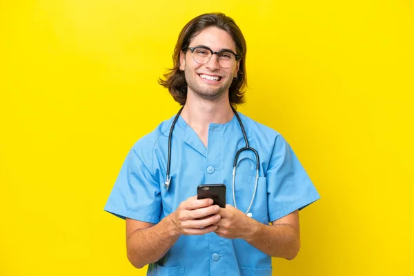 Young Surgeon Caucasian Man Isolated Yellow Background Sending Message Mobile — Stockfoto