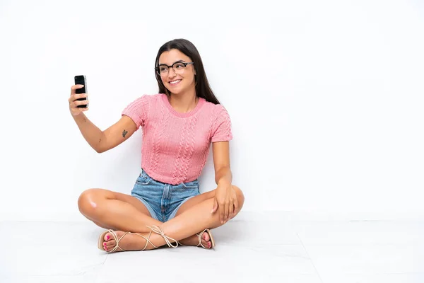 Jovem Caucasiana Sentada Chão Isolada Fundo Branco Fazendo Uma Selfie — Fotografia de Stock