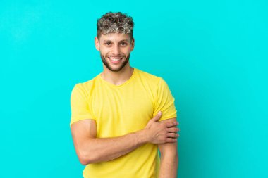 Mavi arka planda izole edilmiş yakışıklı beyaz adam gülüyor.