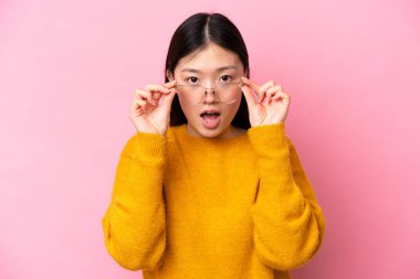 Young Chinese woman isolated on pink background With glasses and surprised expression