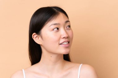 Genç Çinli kadın bej arka planda izole edilmiş. Portre