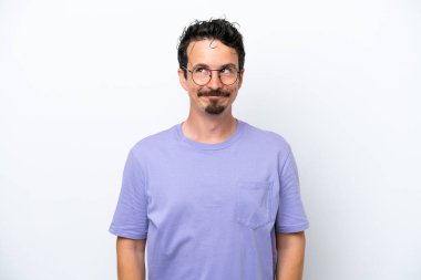 Young man with moustache isolated on white background having doubts while looking up