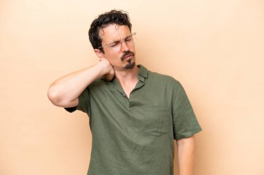 Young caucasian man isolated on beige background with neckache