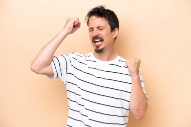 Beyazlı genç bir adam bej arka planda izole edilmiş zaferi kutluyor.