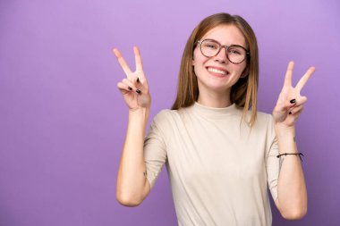 Young English woman isolated on purple background showing victory sign with both hands