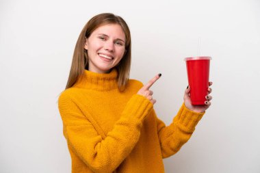 Soda tutan genç İngiliz kadın beyaz arka planda izole edilmiş ve onu işaret ediyor.
