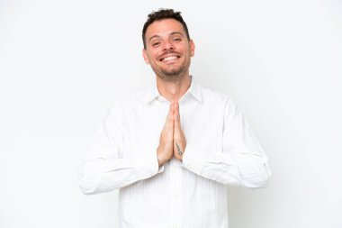 Beyaz arka planda izole edilmiş beyaz, yakışıklı genç bir adam avuç içlerini bir arada tutuyor. İnsan bir şey ister.