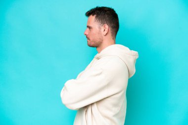 Beyaz tenli yakışıklı adam mavi arka planda, yan pozisyonda izole edilmiş.