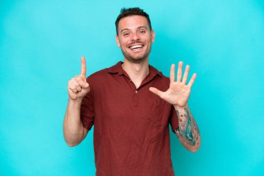 Beyaz tenli yakışıklı adam mavi arka planda izole edilmiş. Parmakları olan altı kişi saydım.