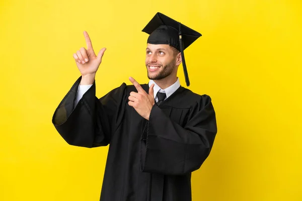 Jeune Diplômé Universitaire Homme Caucasien Isolé Sur Fond Jaune Pointant — Photo