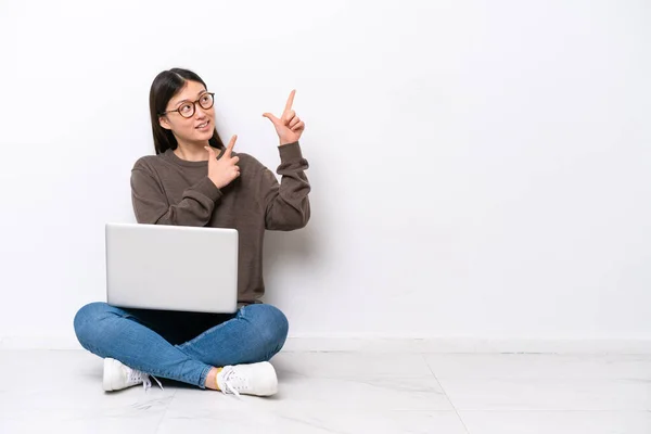 一个拿着笔记本电脑的年轻女人坐在地板上 用食指指尖着一个好主意 — 图库照片