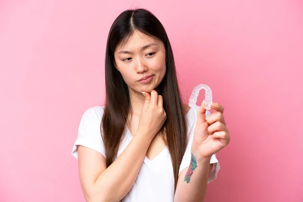 Young Chinese Woman Holding Invisible Braces Isolated Pink Background Sad — Zdjęcie stockowe