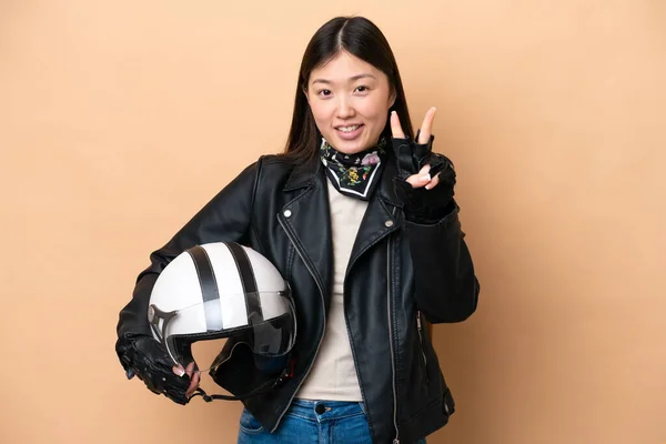 Молодая Китаянка Мотоциклетном Шлеме Бежевом Фоне Улыбается Показывает Знак Победы — стоковое фото