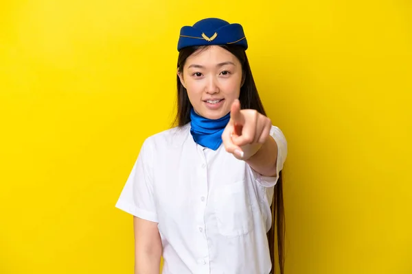 Airplane Chinese woman stewardess isolated on yellow background points finger at you with a confident expression