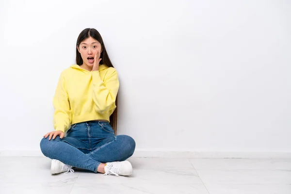 Young Chinese Woman Sitting Floor Isolated White Wall Surprise Shocked — Stock fotografie