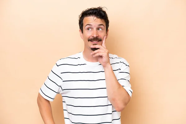 Joven Hombre Caucásico Aislado Sobre Fondo Beige Pensando Una Idea —  Fotos de Stock